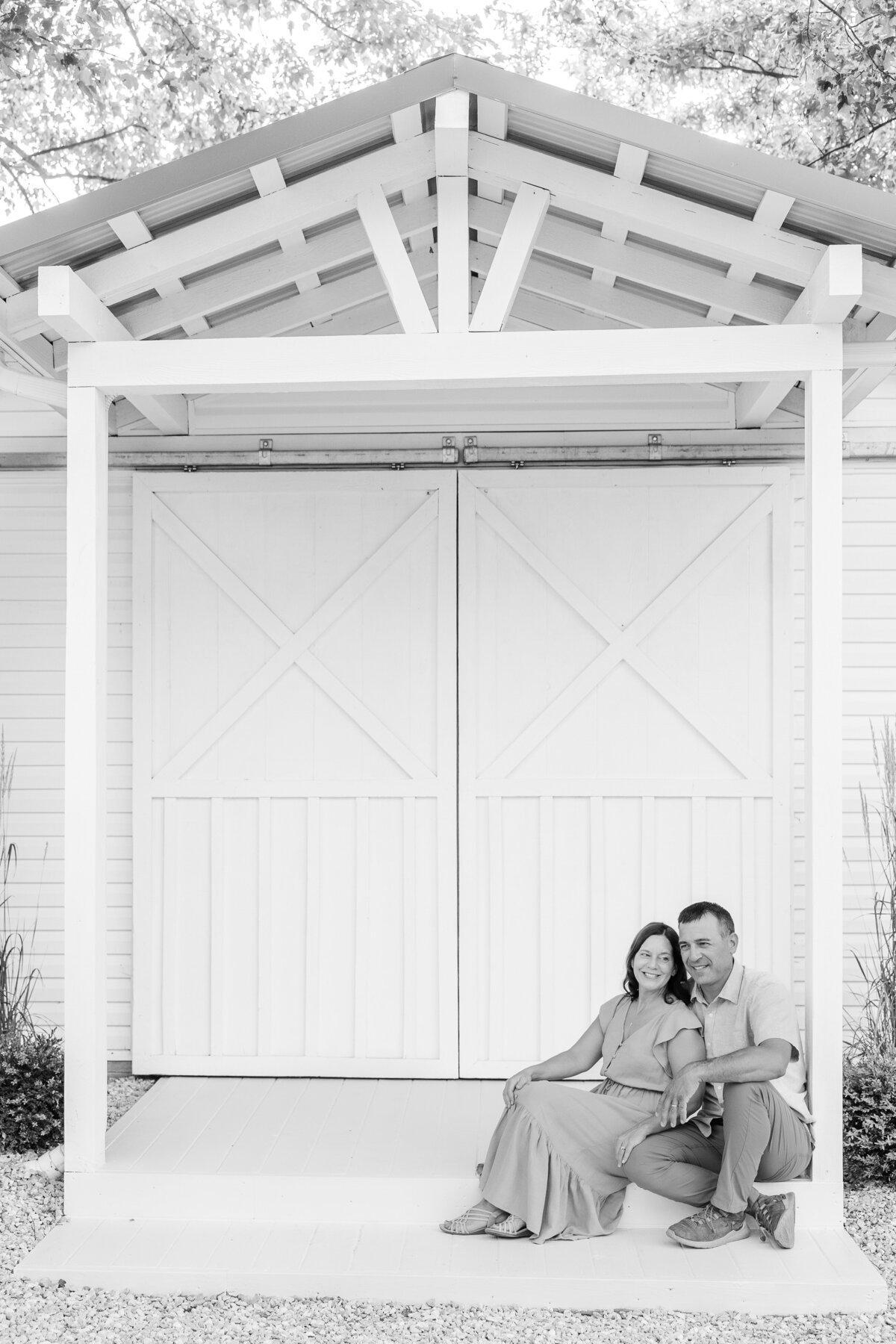 Father and a mother sitting close to one another at a white “outside grand entrance” for a family photography session.