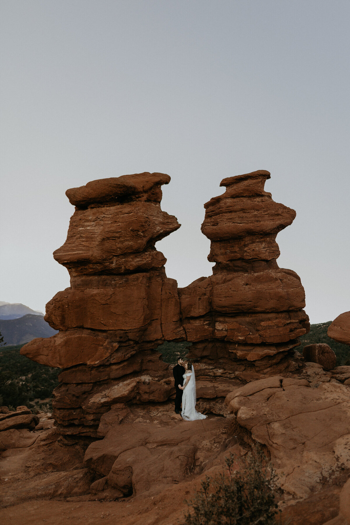 newlyweds standing between red rocks at Garden of the Gods in Colorado