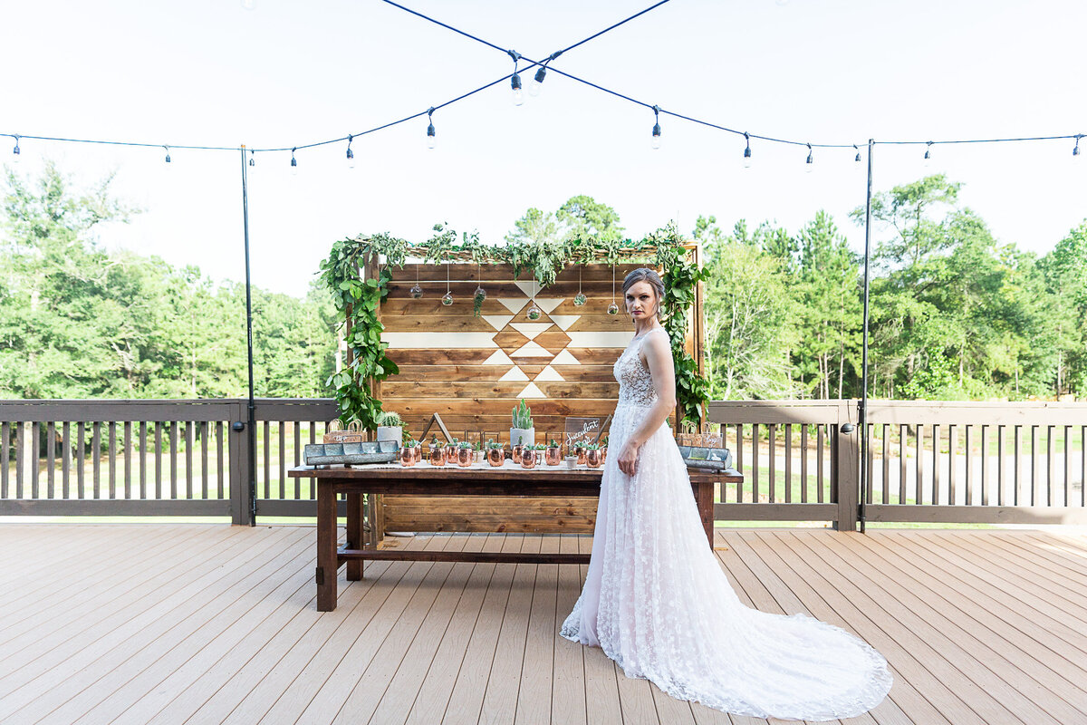 Bride standing in front of a wooden wedding backdrop design