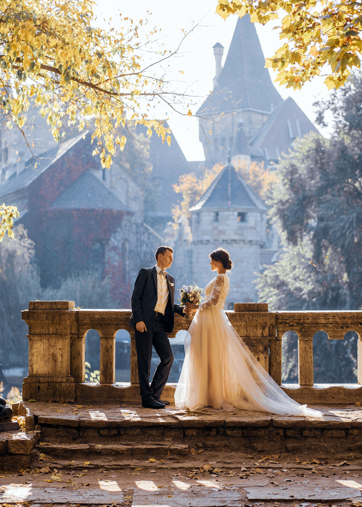 A bride with an organza wedding dress and groom stand in front of a castle in Switzerland.