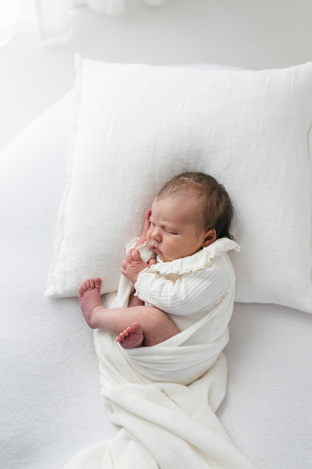 Newborn baby wrapped up and placed ona  pillow sleeping