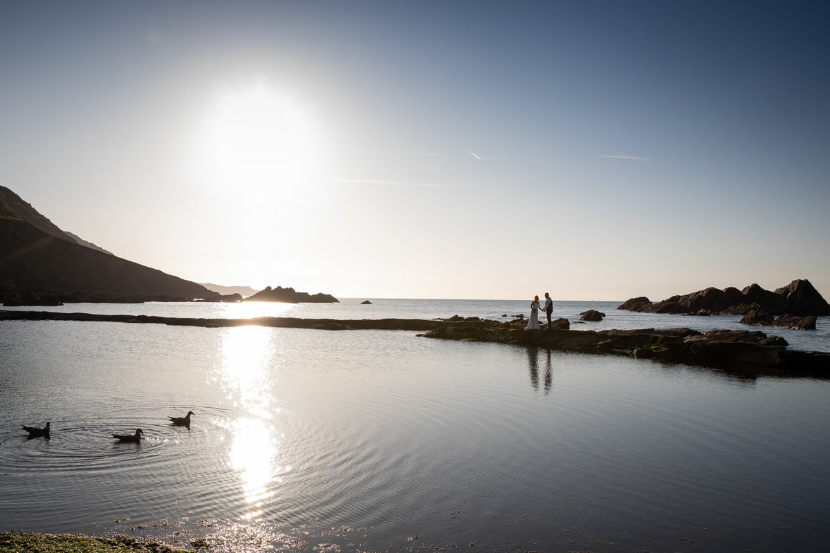 Couple with seagulls by the tidal pools at Tunnels Beaches wedding venue in Devon