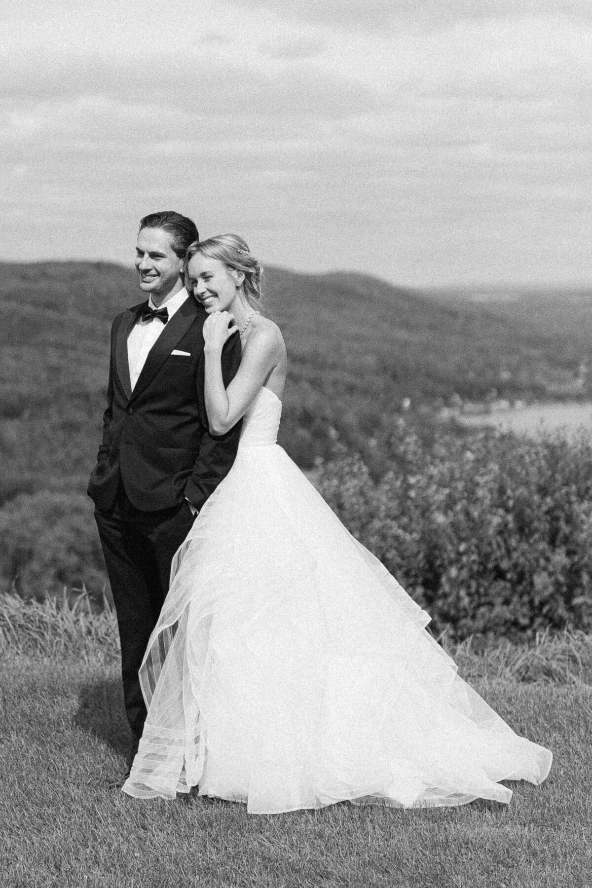 Couple de mariés devant es montagnes, ils sourient, ils sont heureux, ils regardent au loin ensemble. 