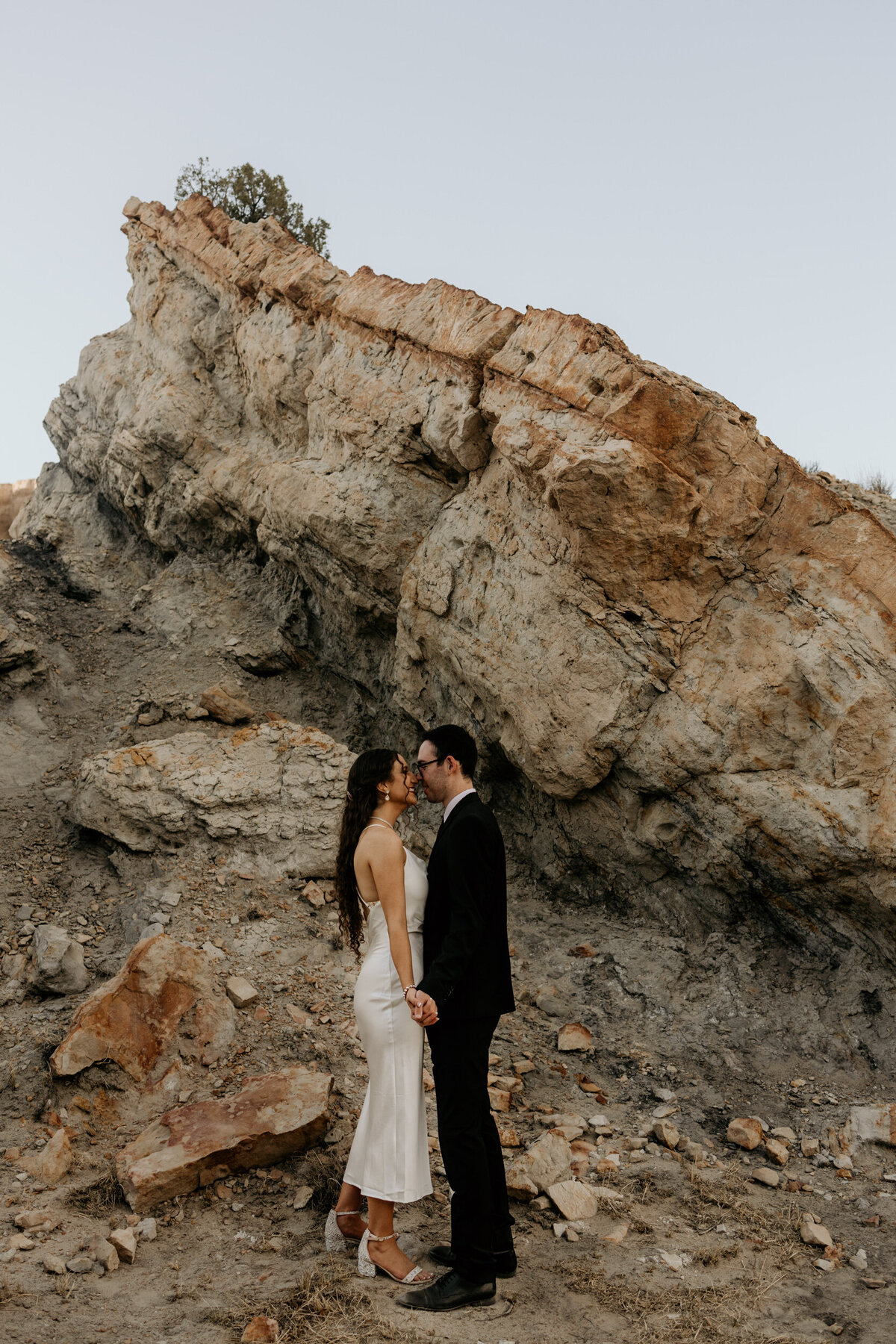 bride and groom kissing in front of colorful rocks in new mexico