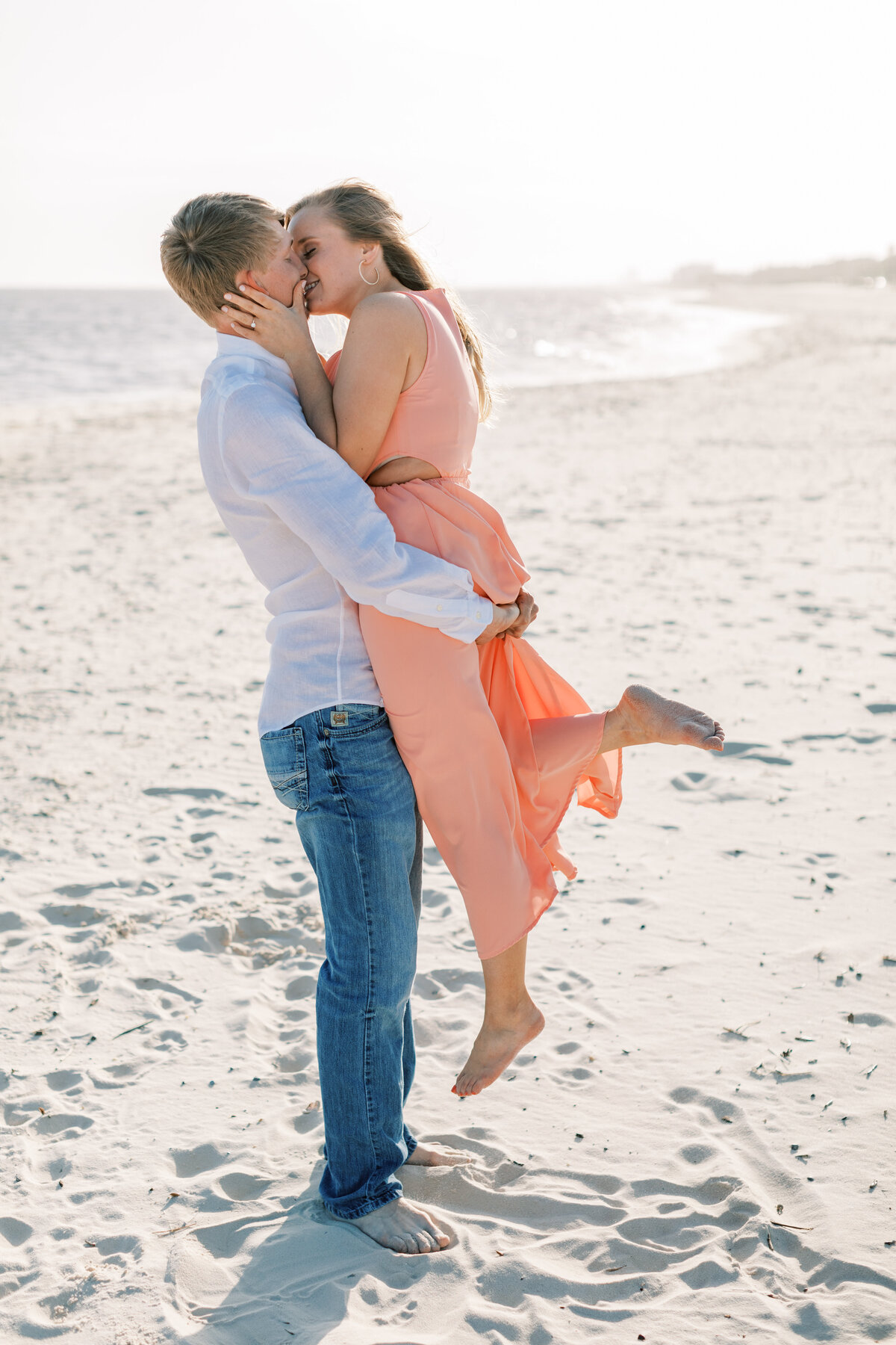 A couple kisses on the white sandy beach.