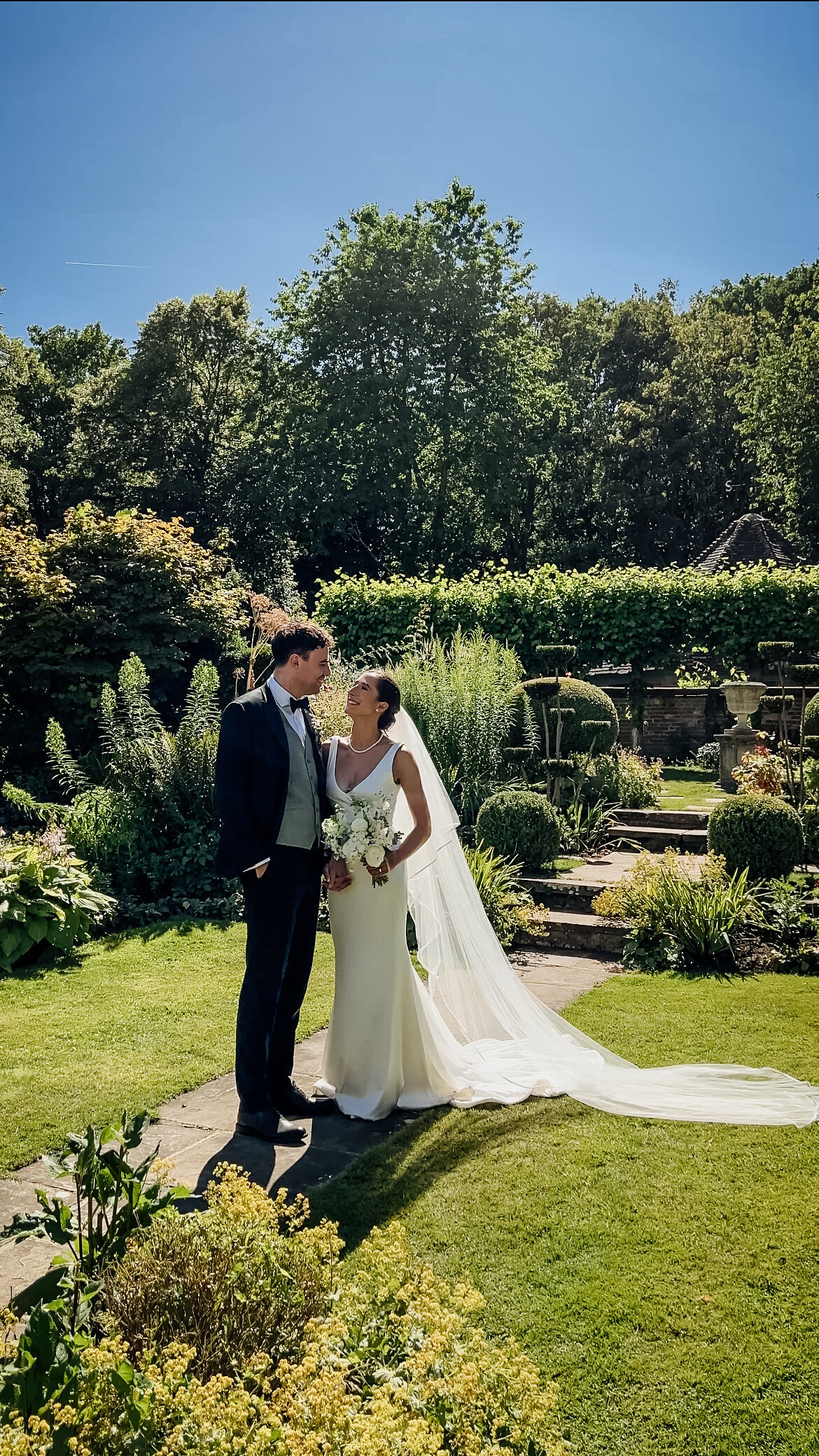 Bride and groom posing in lush garden on their wedding day captured by Suffolk Wedding Content Creator