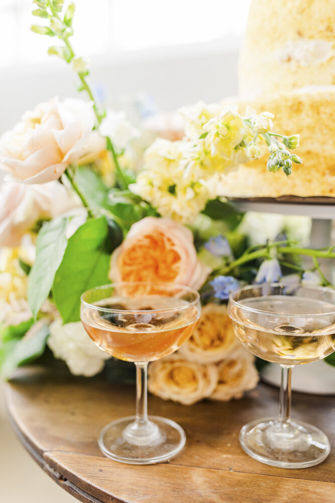 close up photo of orange cocktails and floral arrangements on a table