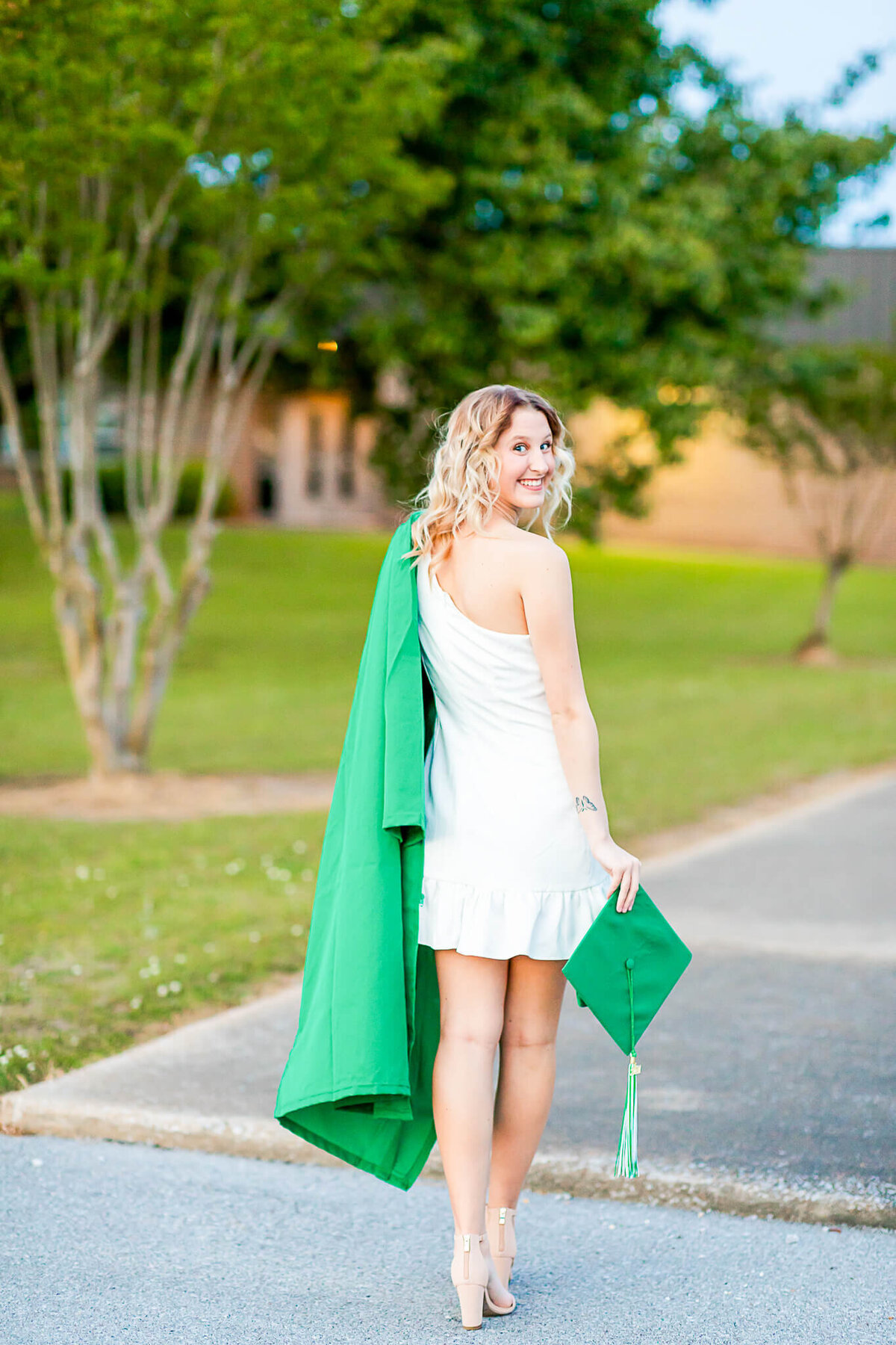 Graduating senior walks her high school sidewalks with her cap and gown
