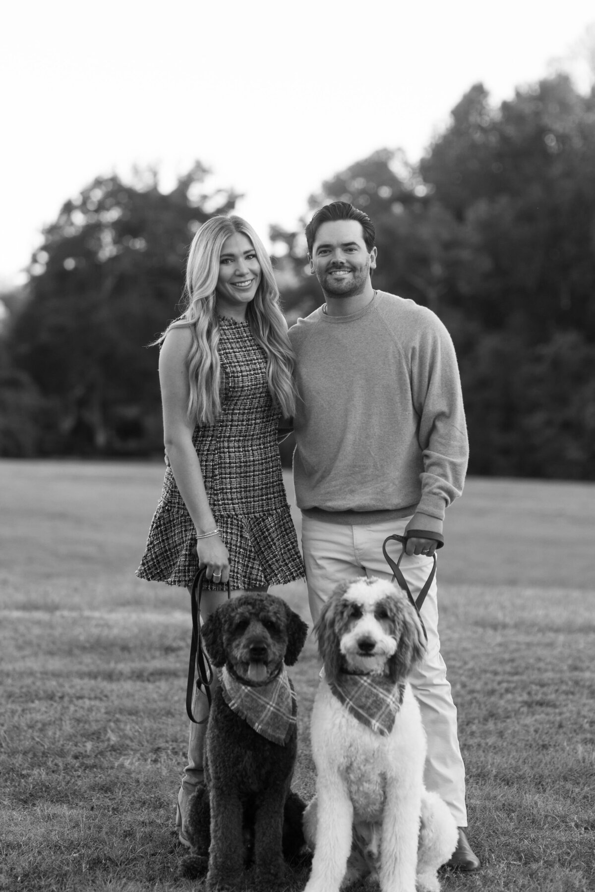 Black and white photo of a man and woman holding their dogs on leashes