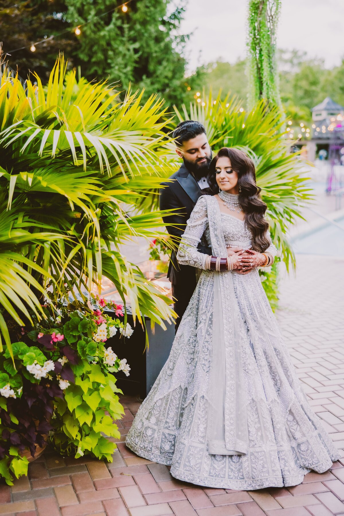 south asian sikh bride and groom embrace in front of palm trees at the crest hollow country club in ny 