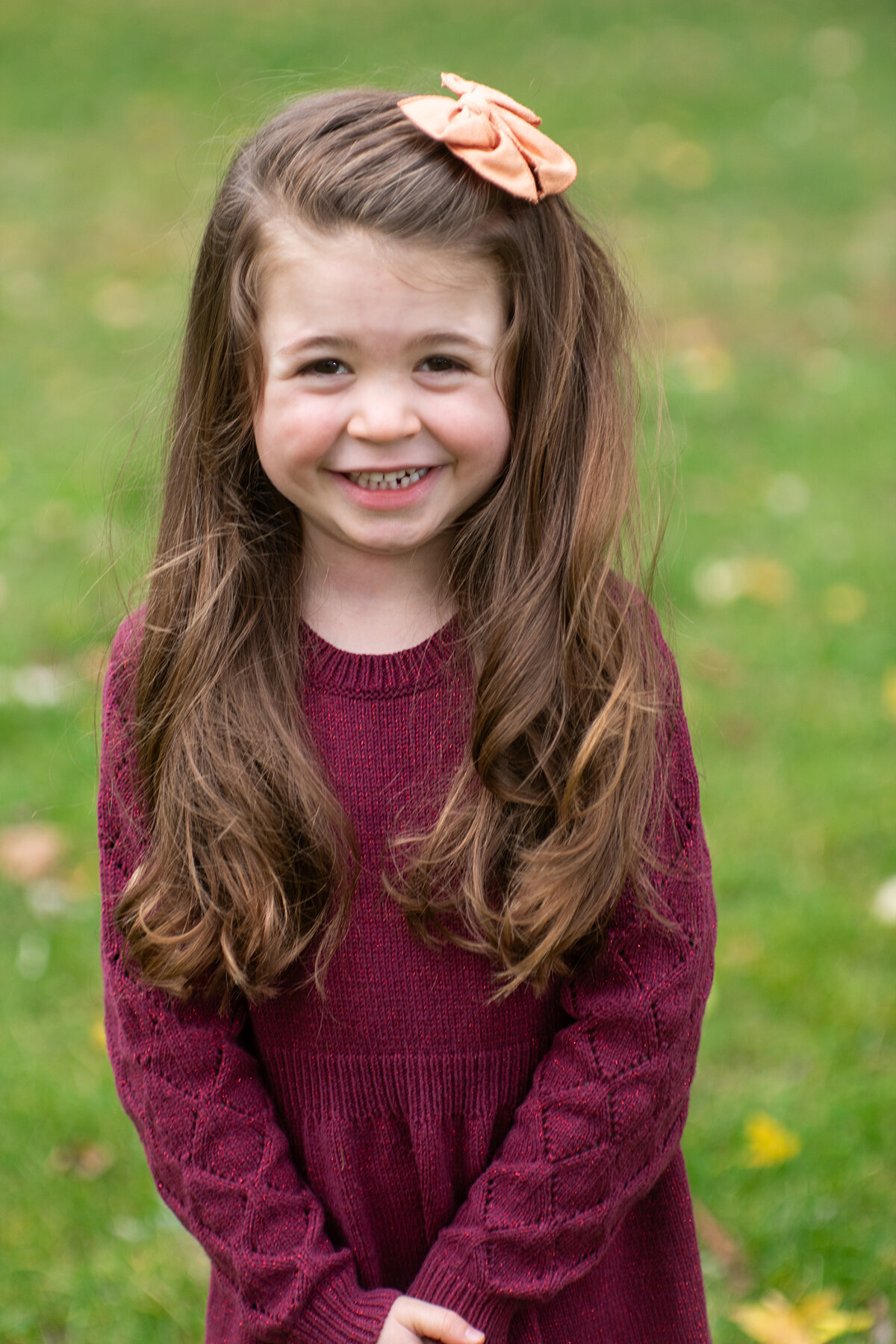young girl smiles outside in grassy field