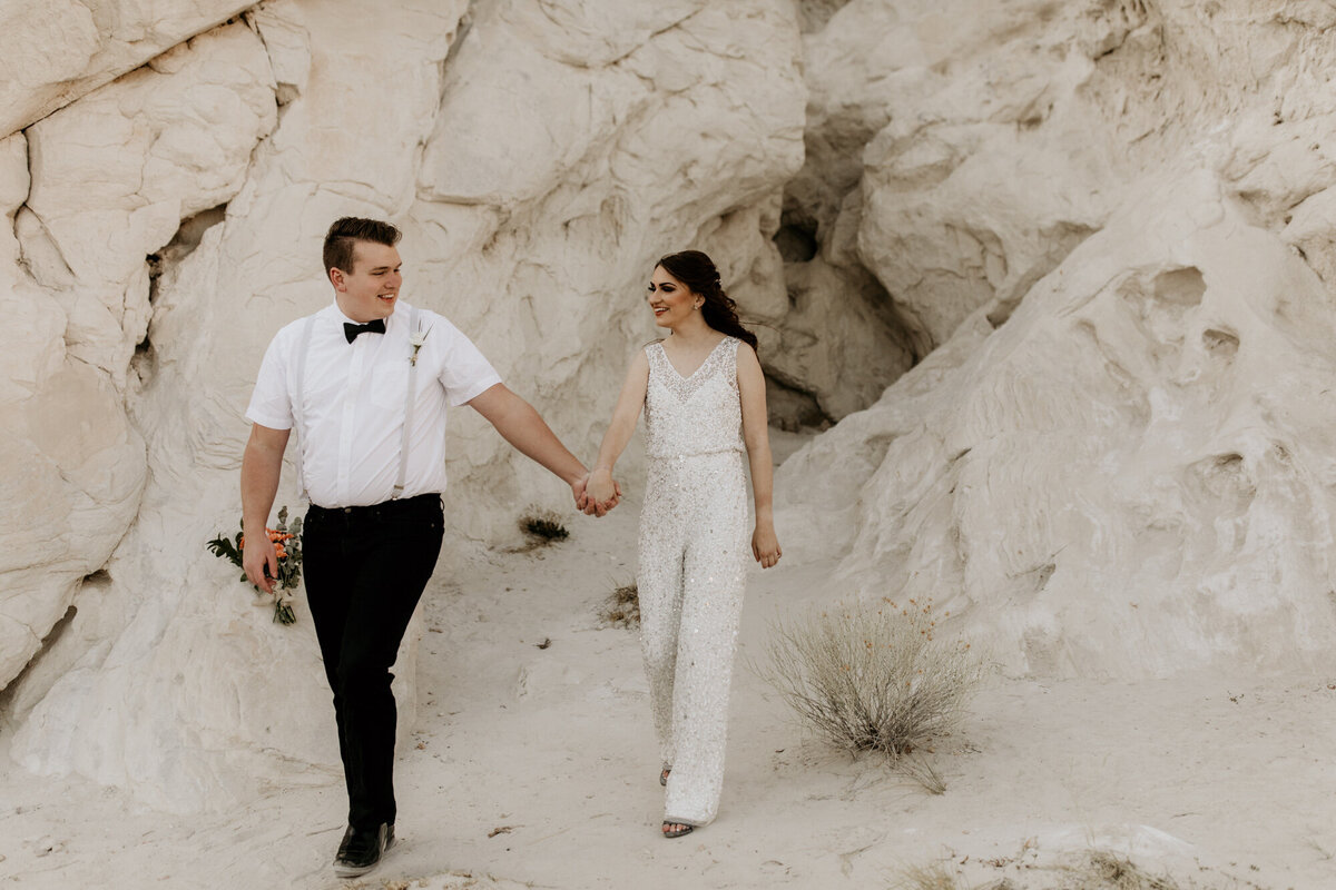 bride and groom walking through New Mexico white rocks