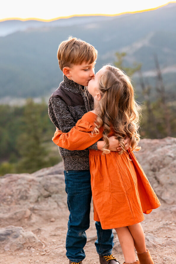 Two siblings kiss each other during their family photos.