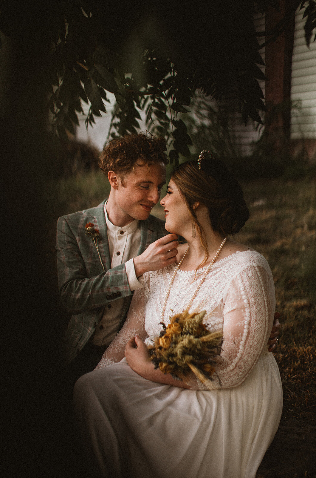 wedding couple kisses through the leaves of a tree 