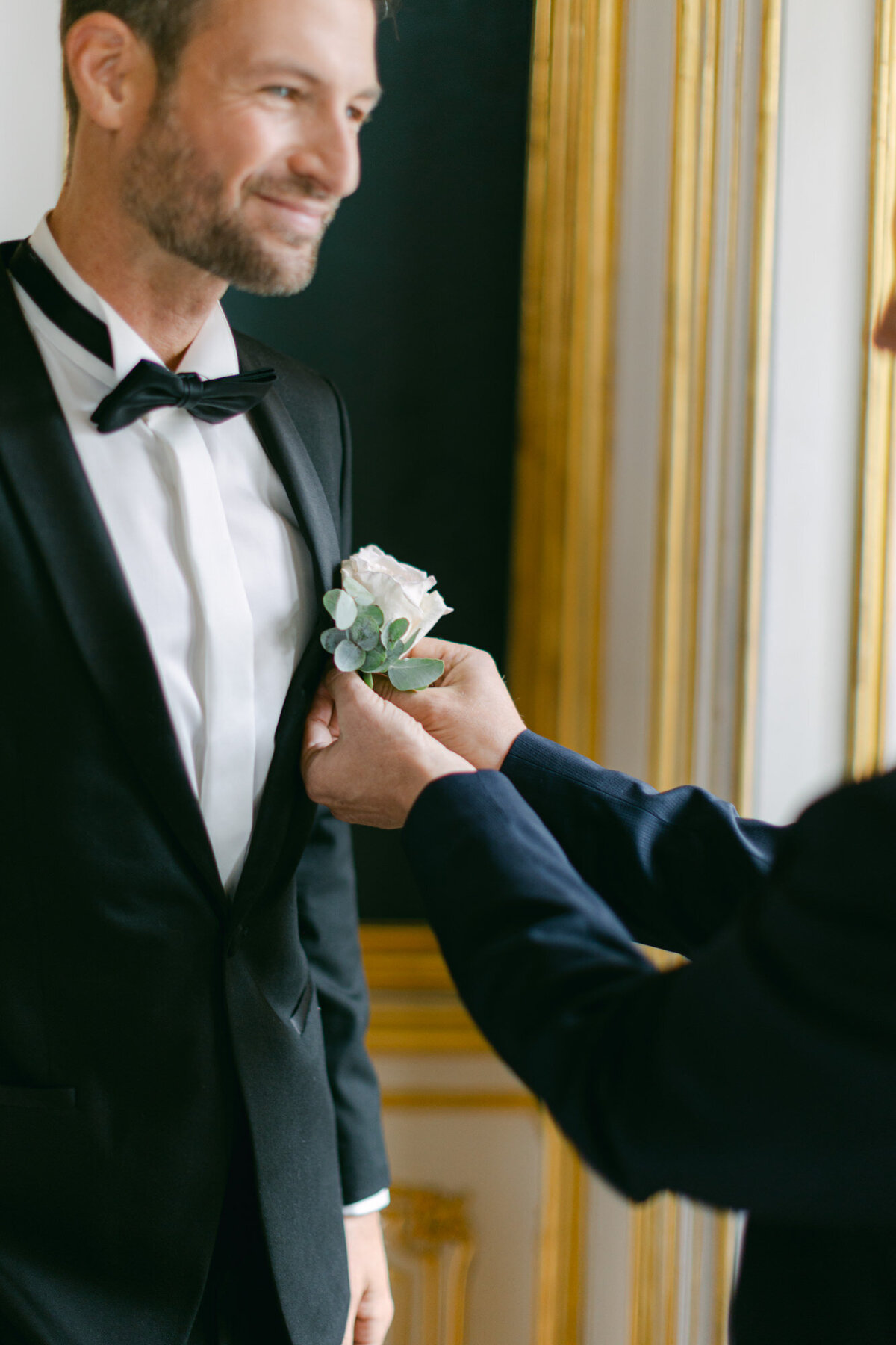 Groom and his best man fixing the wedding boutonniere at luxury palace Coburg in Vienna