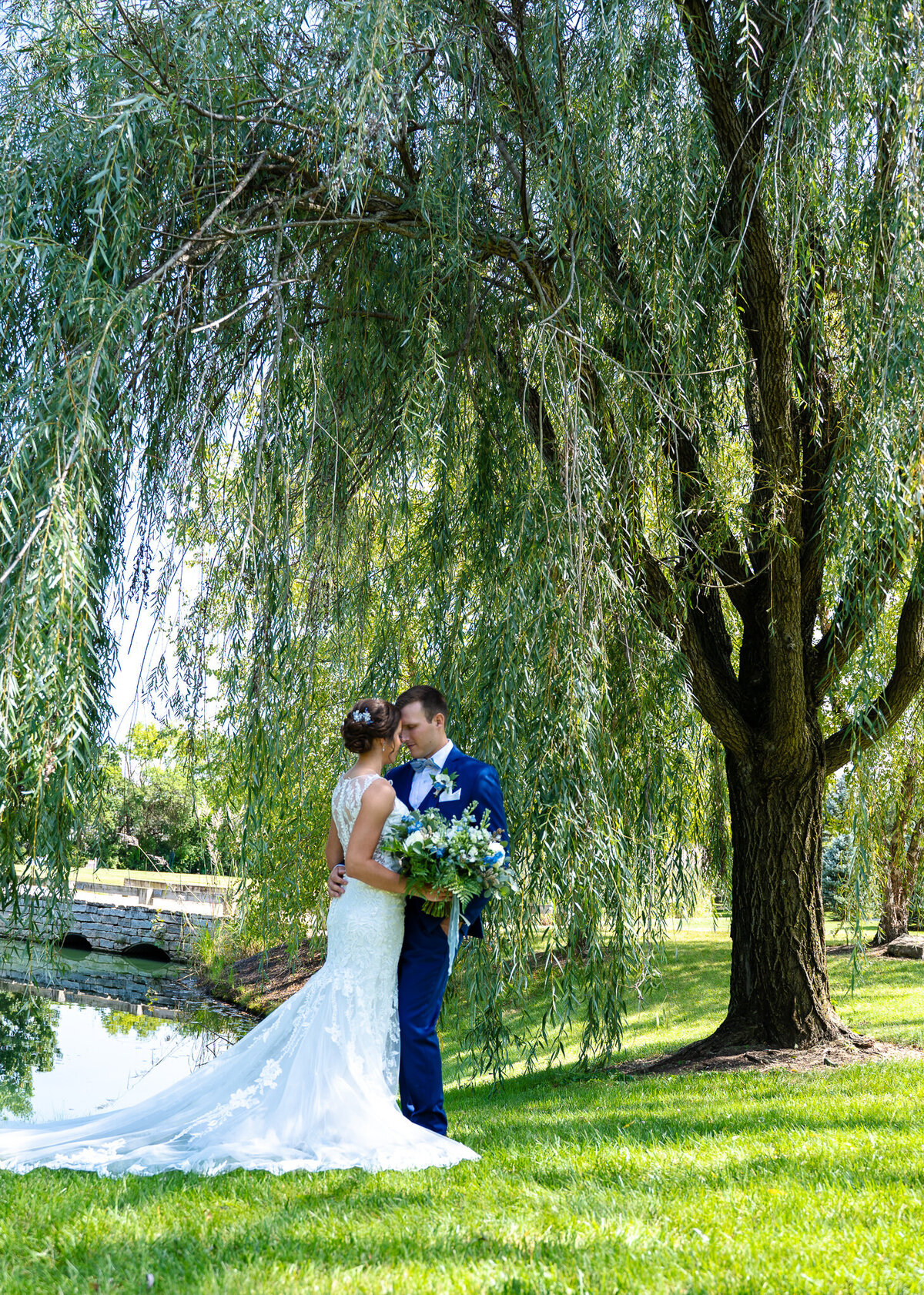 Bride and groom, Michaela and Bryan, touch foreheads under a beautiful weeping willow tree at Everal Barn & Homestead as they wait for their ceremony at Saint Paul Catholic Church and reception at The Estate at New Albany to begin.