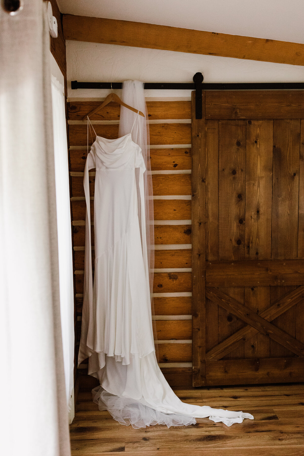 Bridal gown hung against brick wall and wooden door.