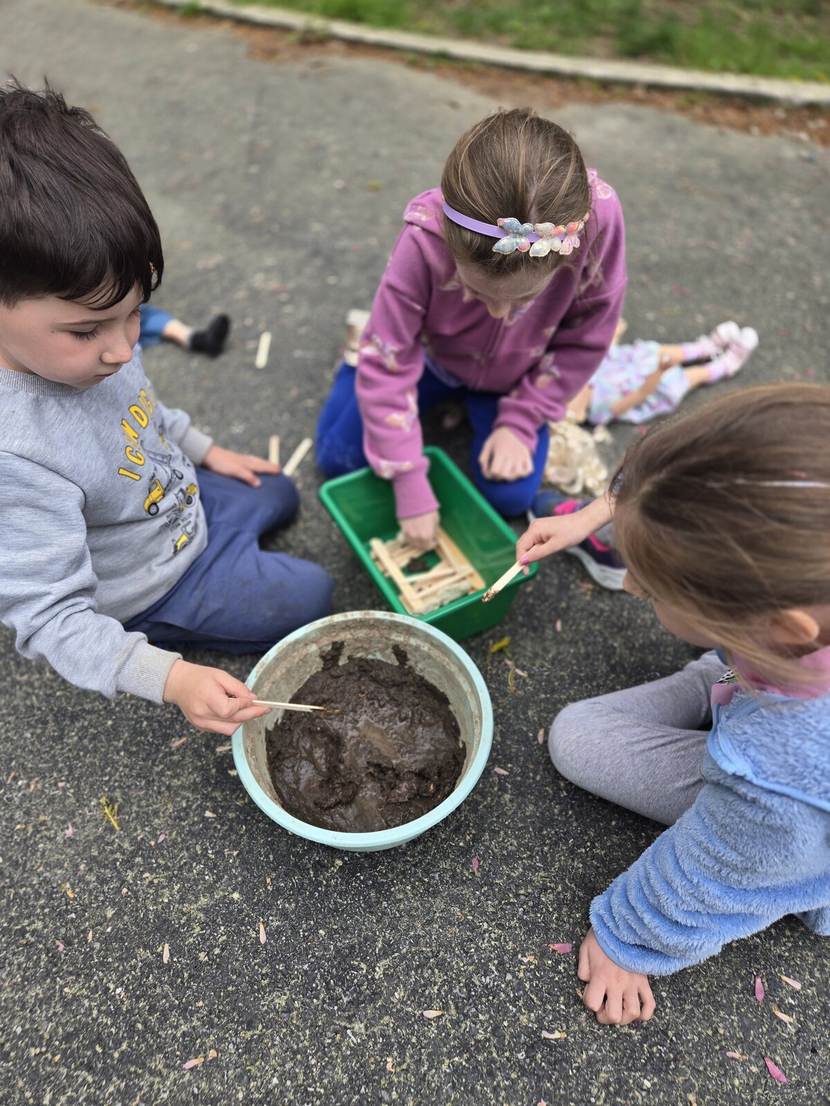 Young children digging and investigating together outdoors at ROOTS