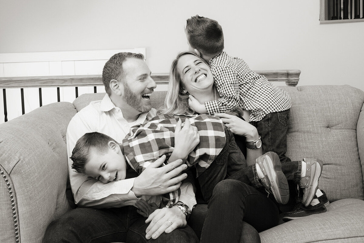 Two kids climbing on their parents as they all laugh 