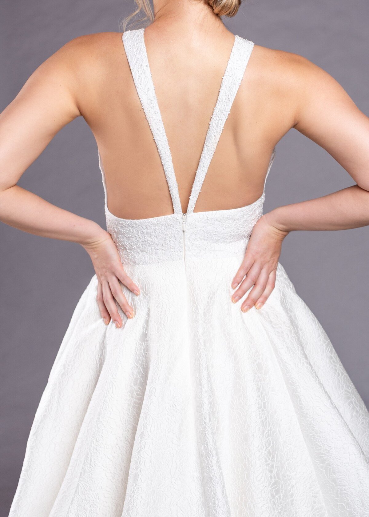 A close-up of the back shows how the ballgown wedding dress's straps come over the shoulders and meet at the zipper to form a V.