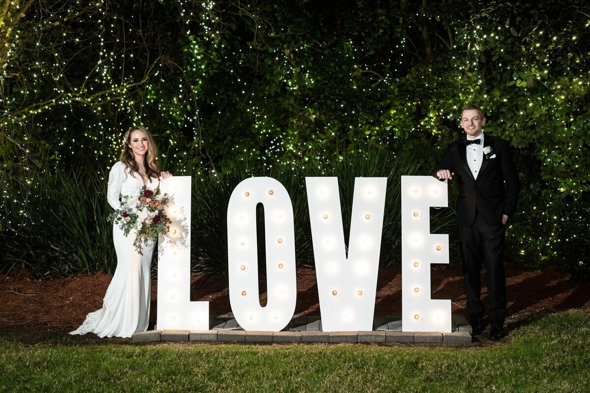 Bride and groom standing by love sign at Southern Oaks