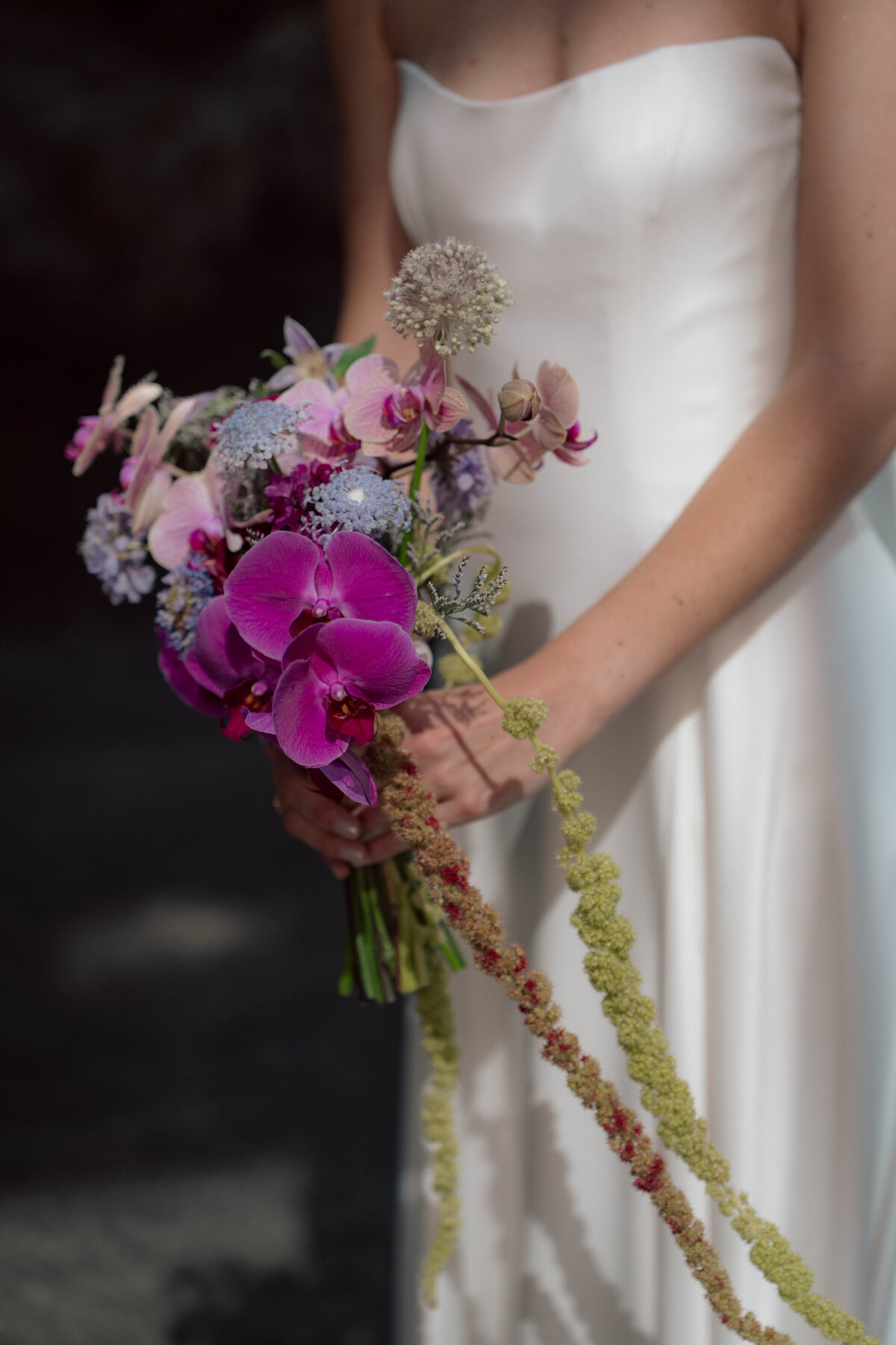 Close-up of bride holding modern colorful bouquet with orchids and pastel florals