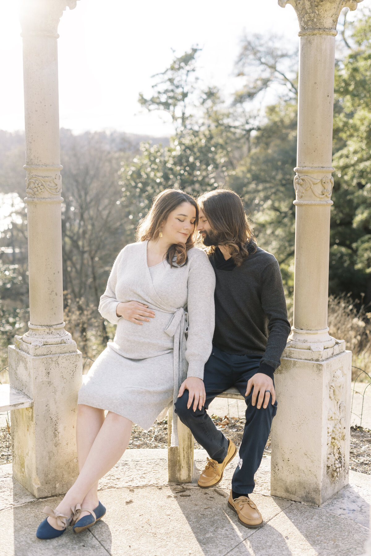 Richmond maternity photography | Light and airy photo of a pregnant mother and her husband is sitting together in a golden lit gazebo touching their temples together by Jacqueline Aimee Portraits