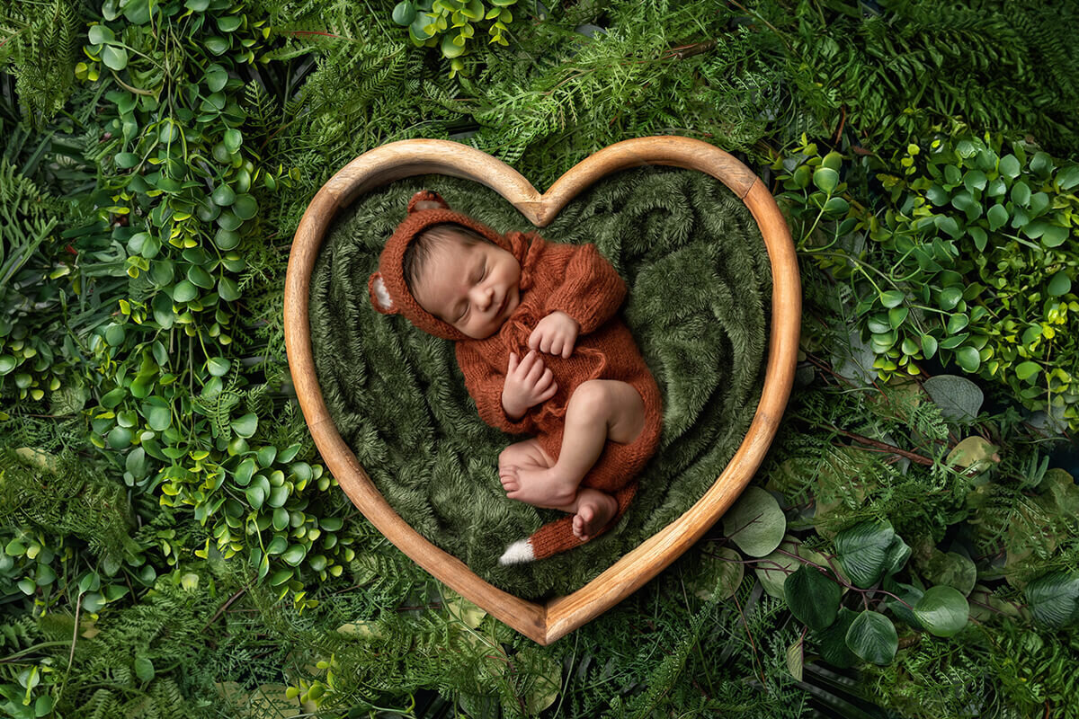 newborn baby laying in a heart bowl