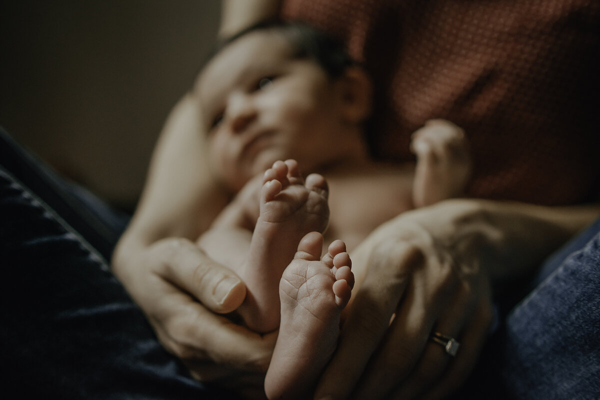 Verona B Photography captures baby details of a newborn – baby feet as baby is held in her mother’s lap at in-home newborn session near Akron, Ohio. Absolutely nothing as cute as baby feet!