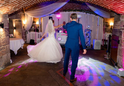 A bride and groom dancing in a brick room