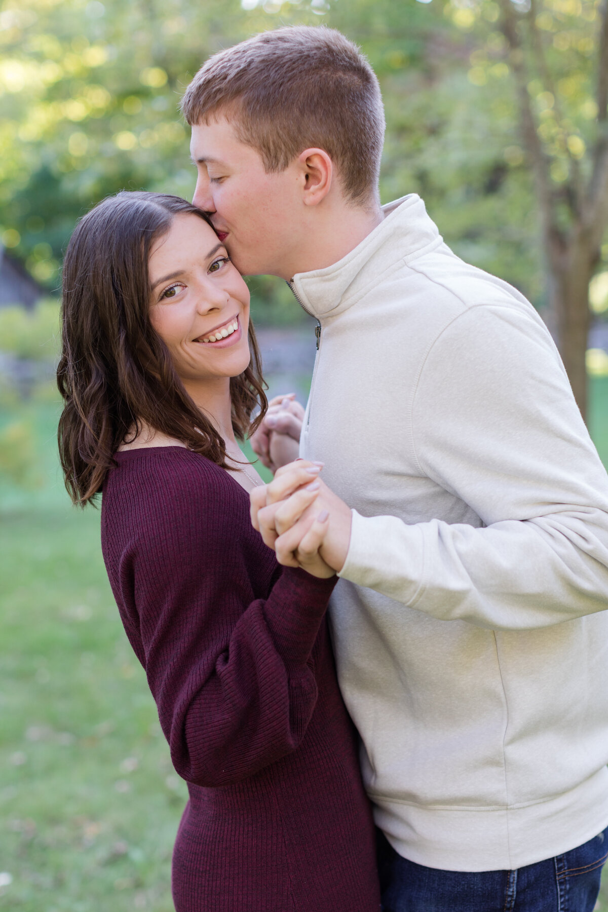 Engaged couple holding each other with the bride smiling at the camera