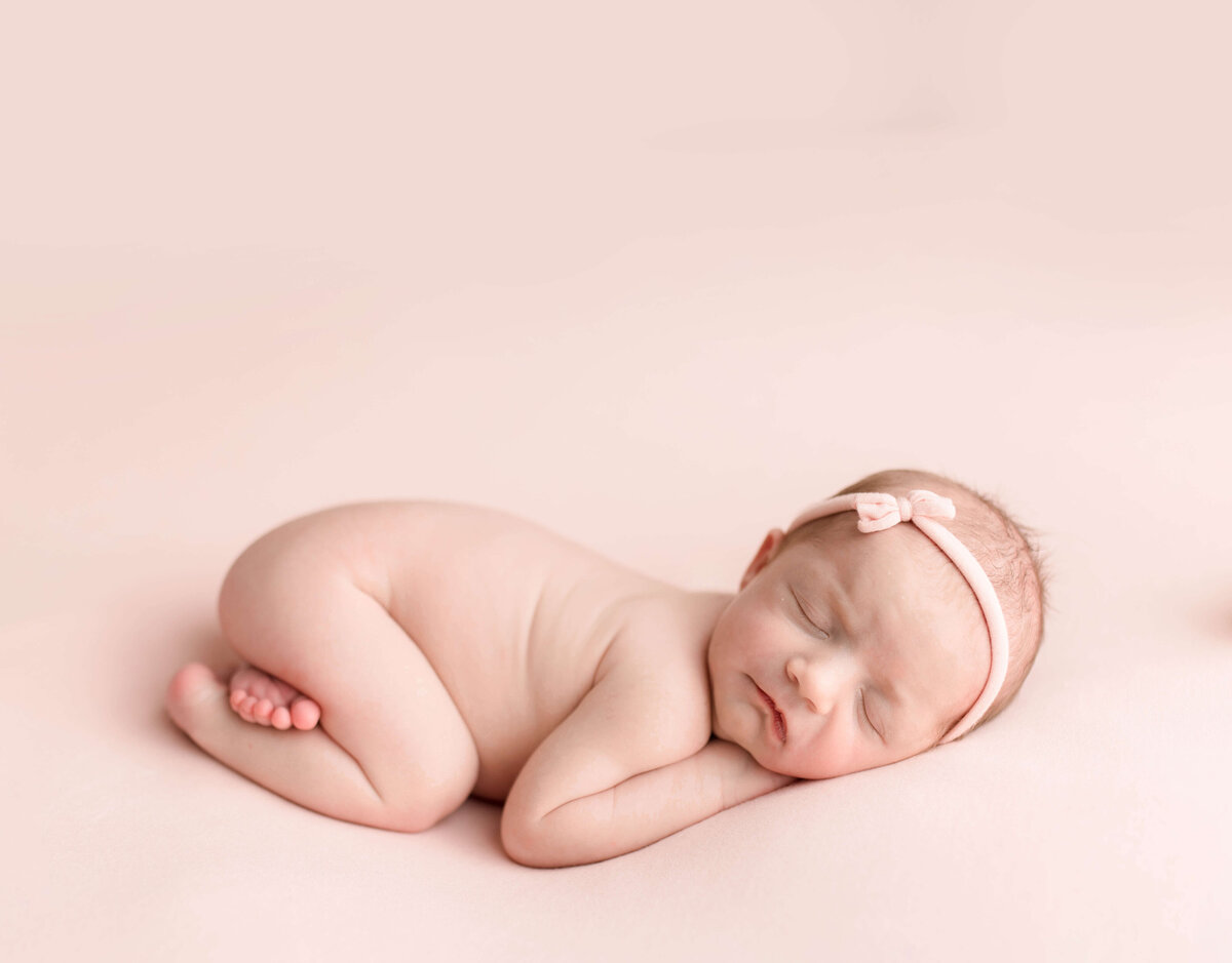 Newborn girl on pink with pink bow