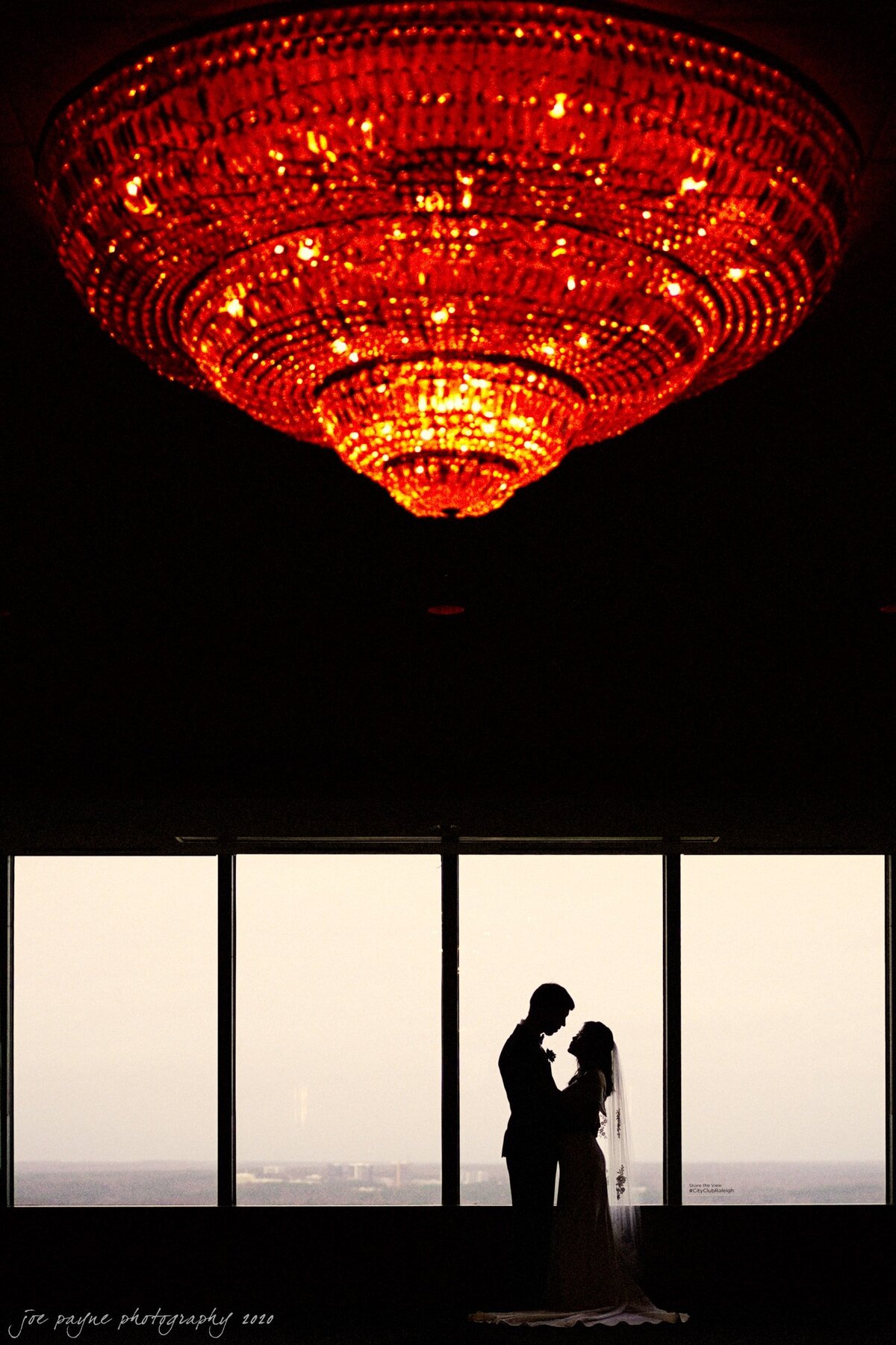 Silhouette of a couple set against large windows overlooking the city.