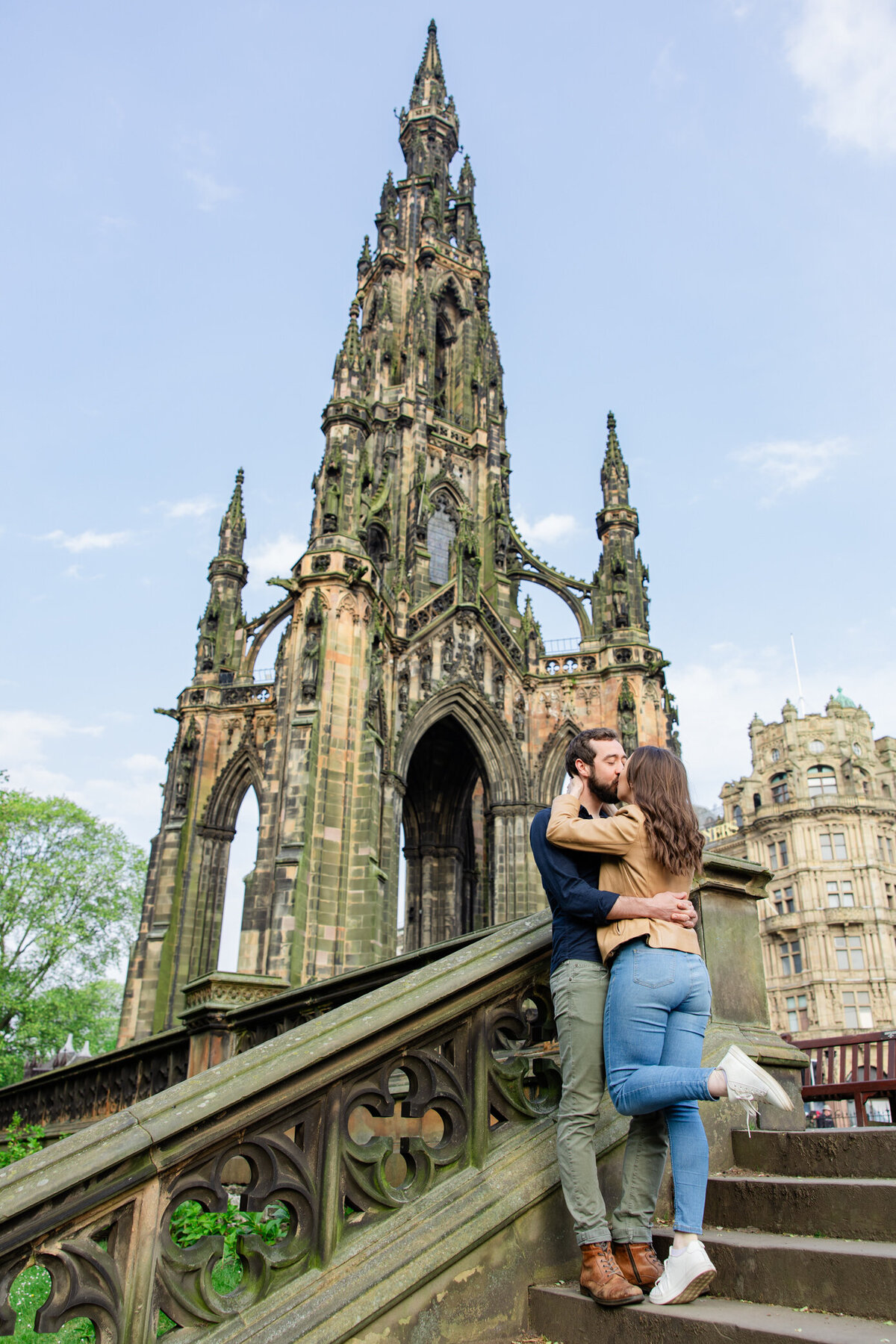 engaged couple kisses in front of spire