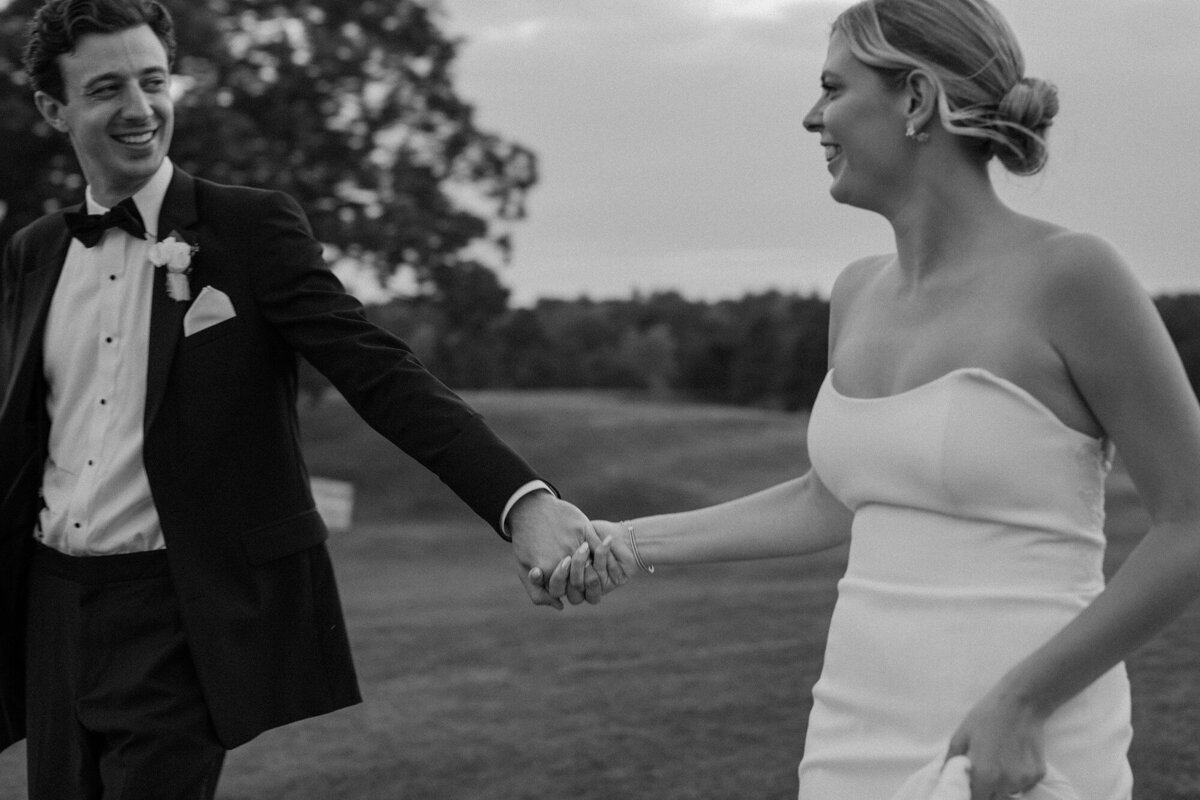 bride and groom running towards the camera on their wedding day, smiling and holding hands