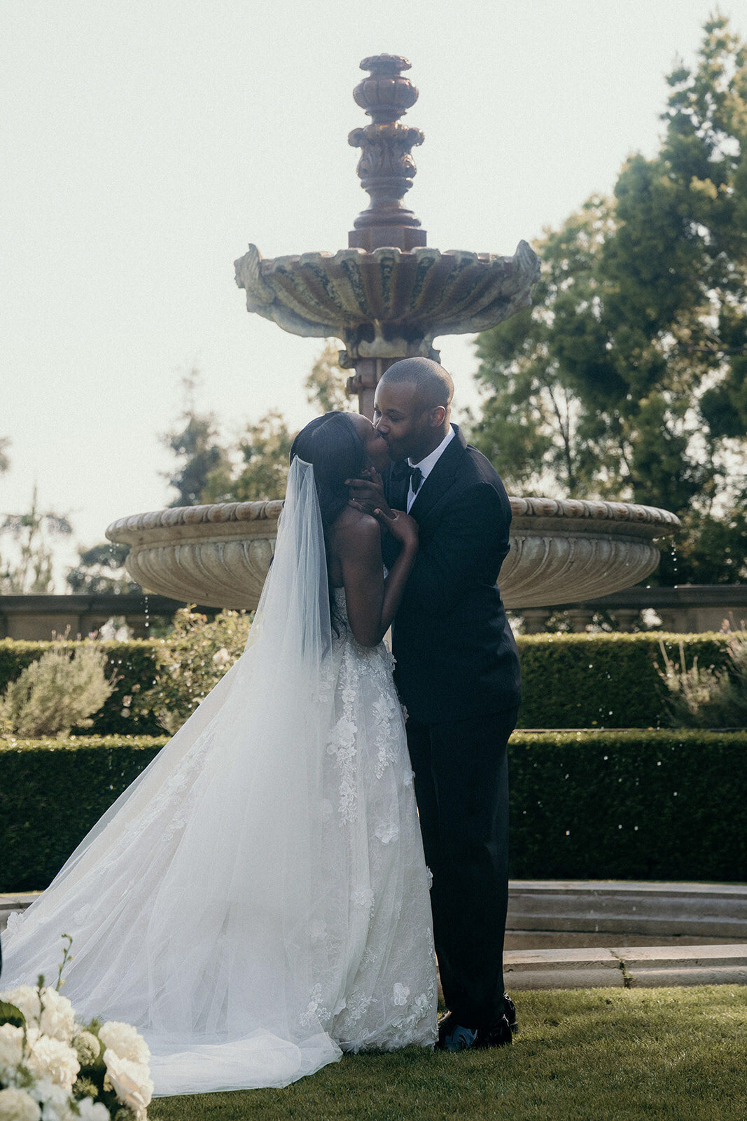First kiss of bride and groom at outdoor wedding in Los Angeles.