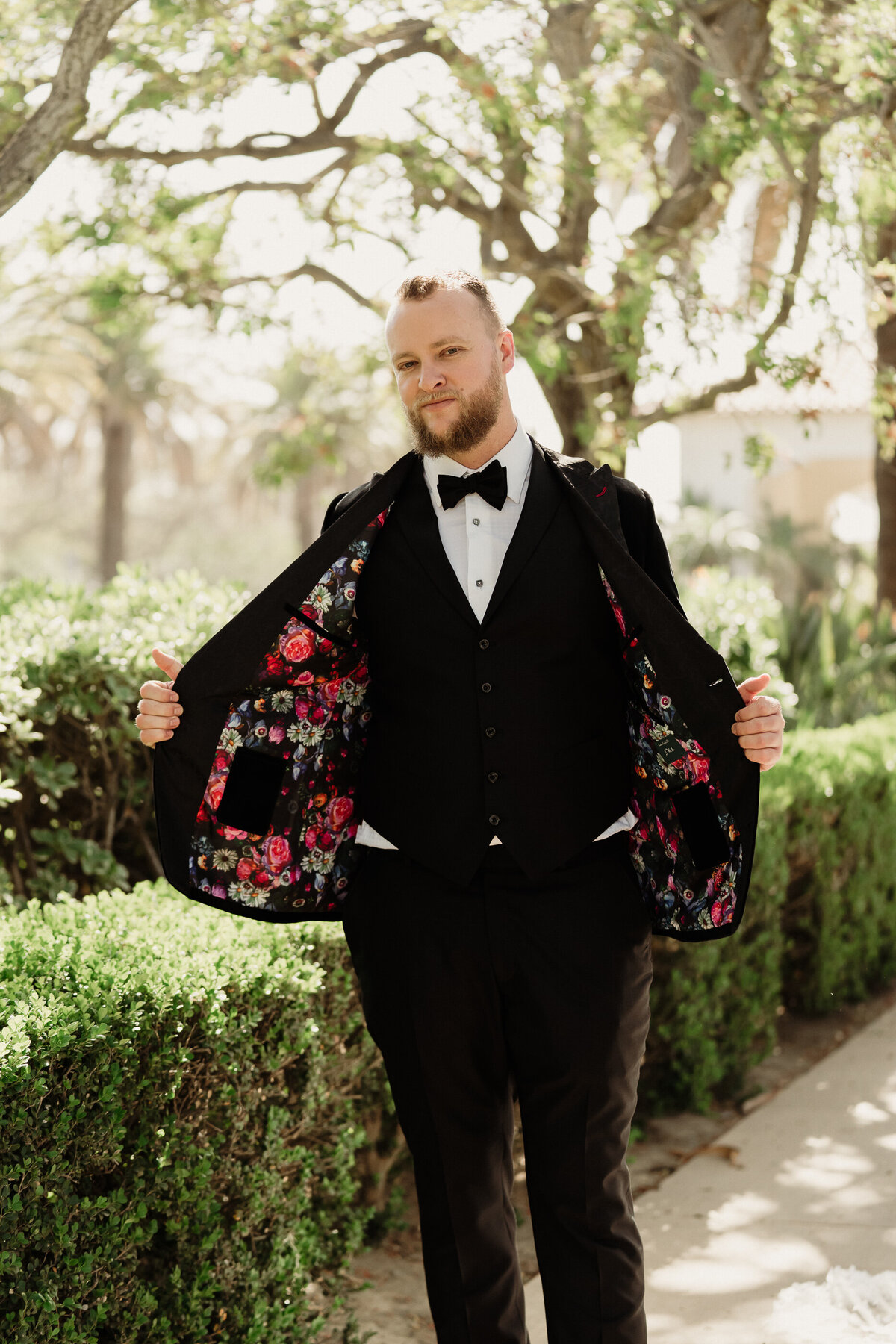 groom wearing a custom black wedding tuxedo showing off the custom lining on the inside of his jacket at spanish hills country club captured by los angeles wedding photographer magnolia west photography