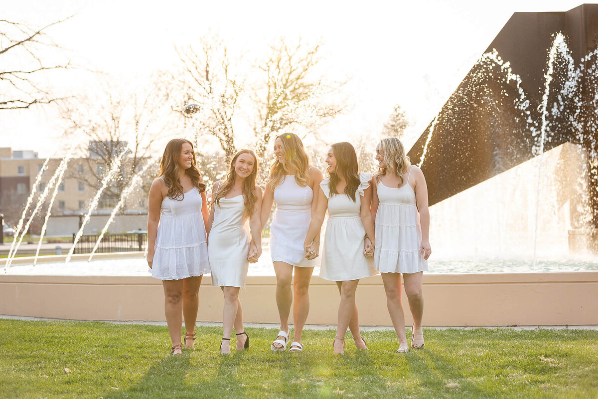 Five girls walking in front of a water fountain during peak golden hour at MSU, Mankato.