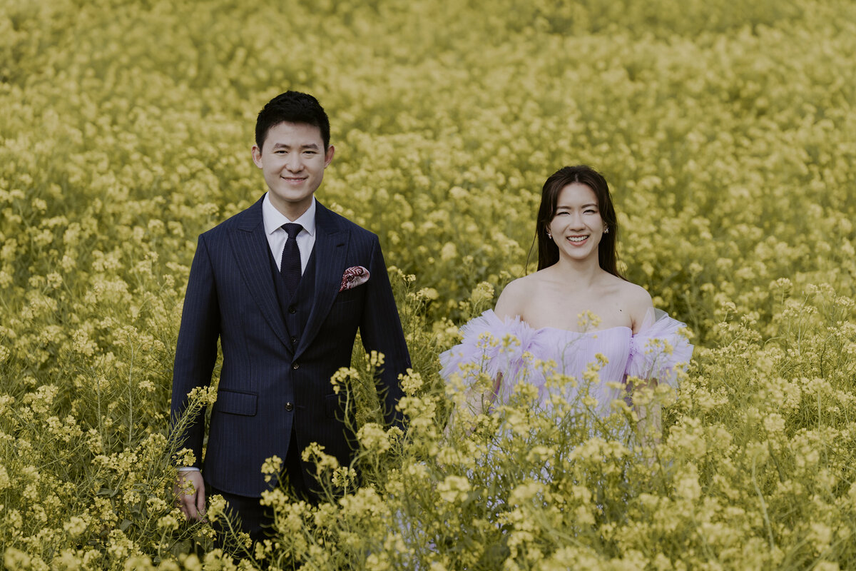 the couple smiling at the camera in the yellow canola fields of sanbangsan jeju island south korea