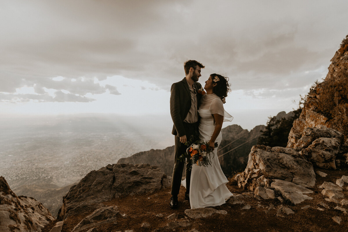 bride and groom looking down at the city of Albuquerque from the Sandia Mountains