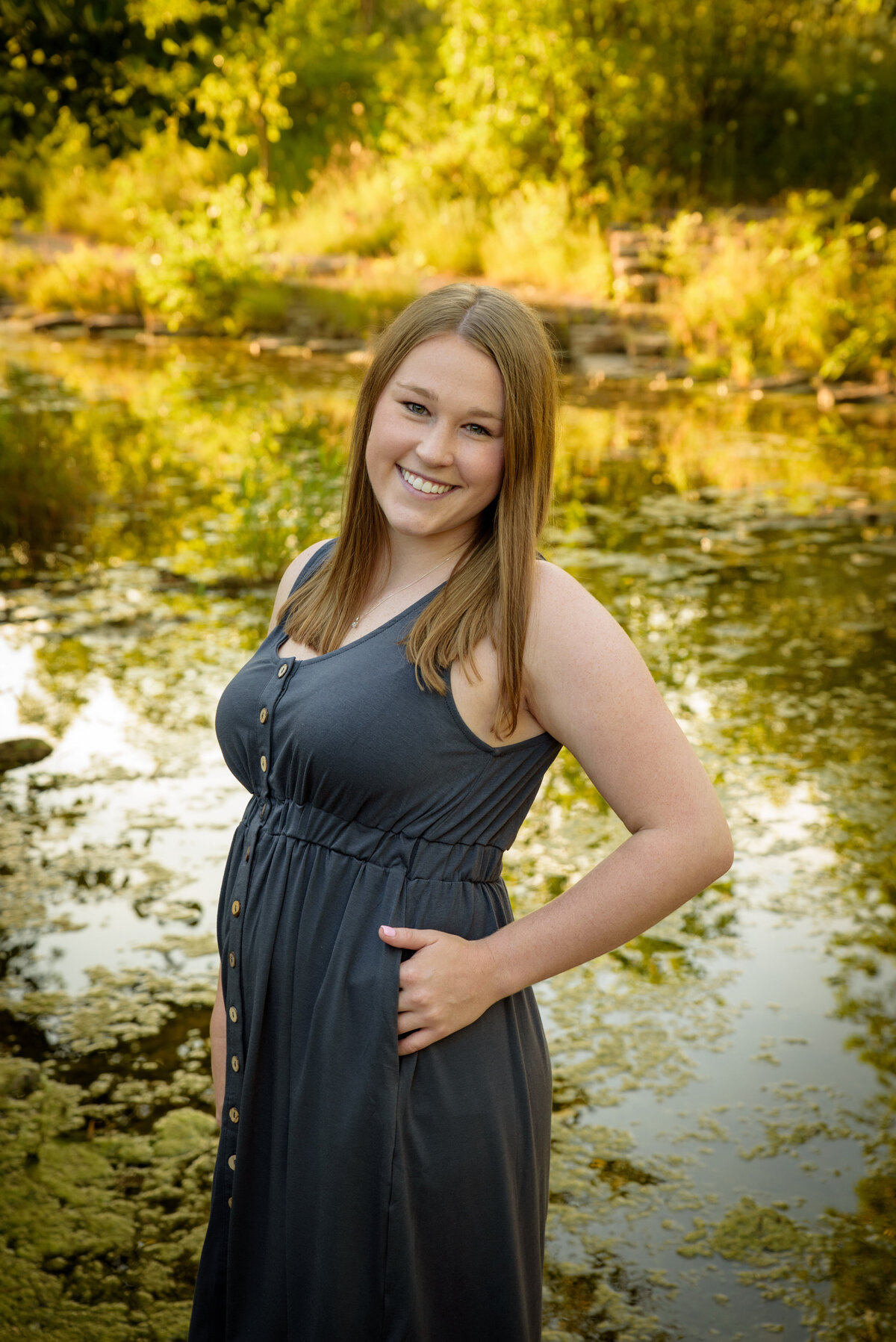 Young woman with long blonde hair and a gray dress standing near the creek at Fonferek Glen County Park near Green Bay, Wisconsin