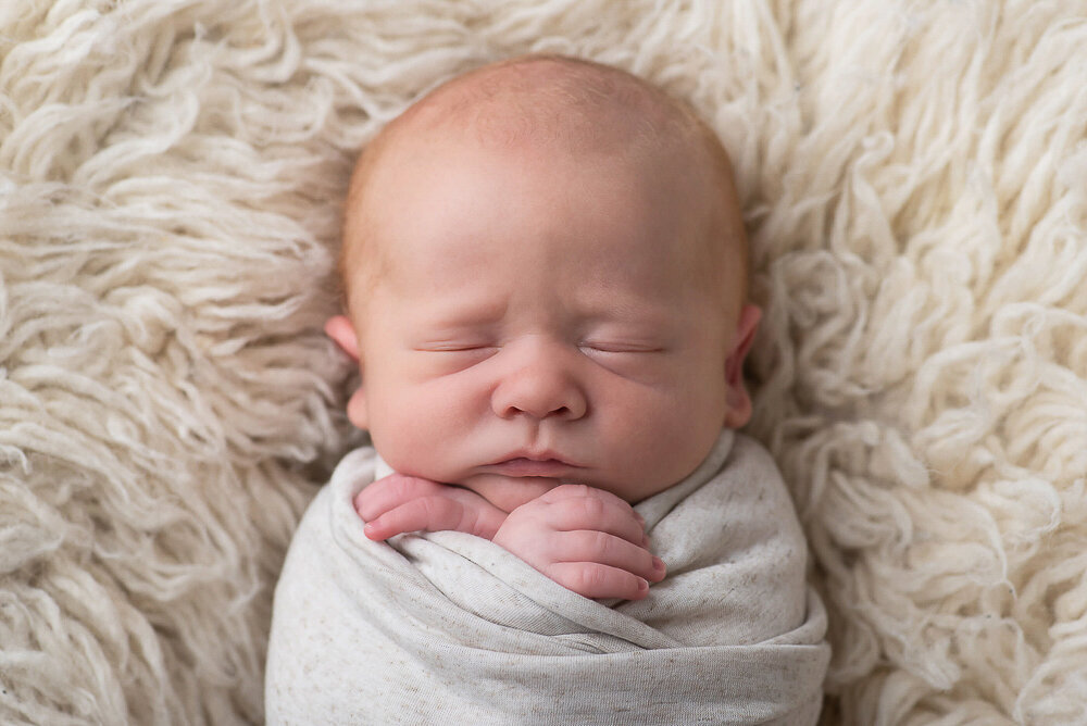 newborn baby boy wrapped in a beige.