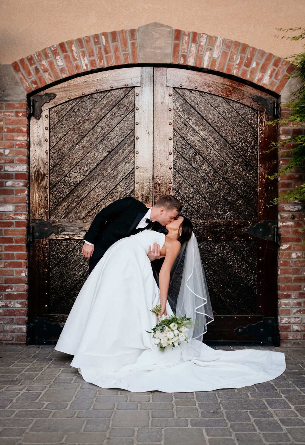 Groom dipping bride for a kiss in front of the Palm Event Center in Pleasanton, CA, during a spring wedding.
