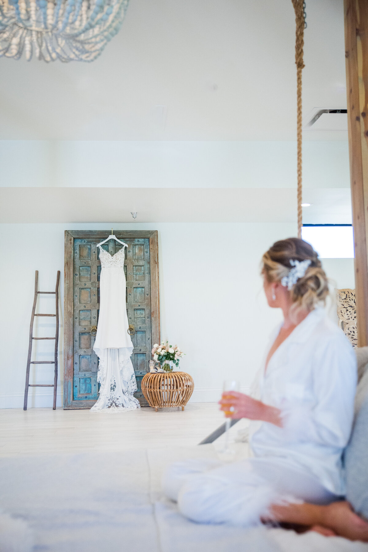 A bride sits in the getting ready space of Denver wedding venue, The Oaks at Plum Creek, and stares at her wedding dress hanging on the door.