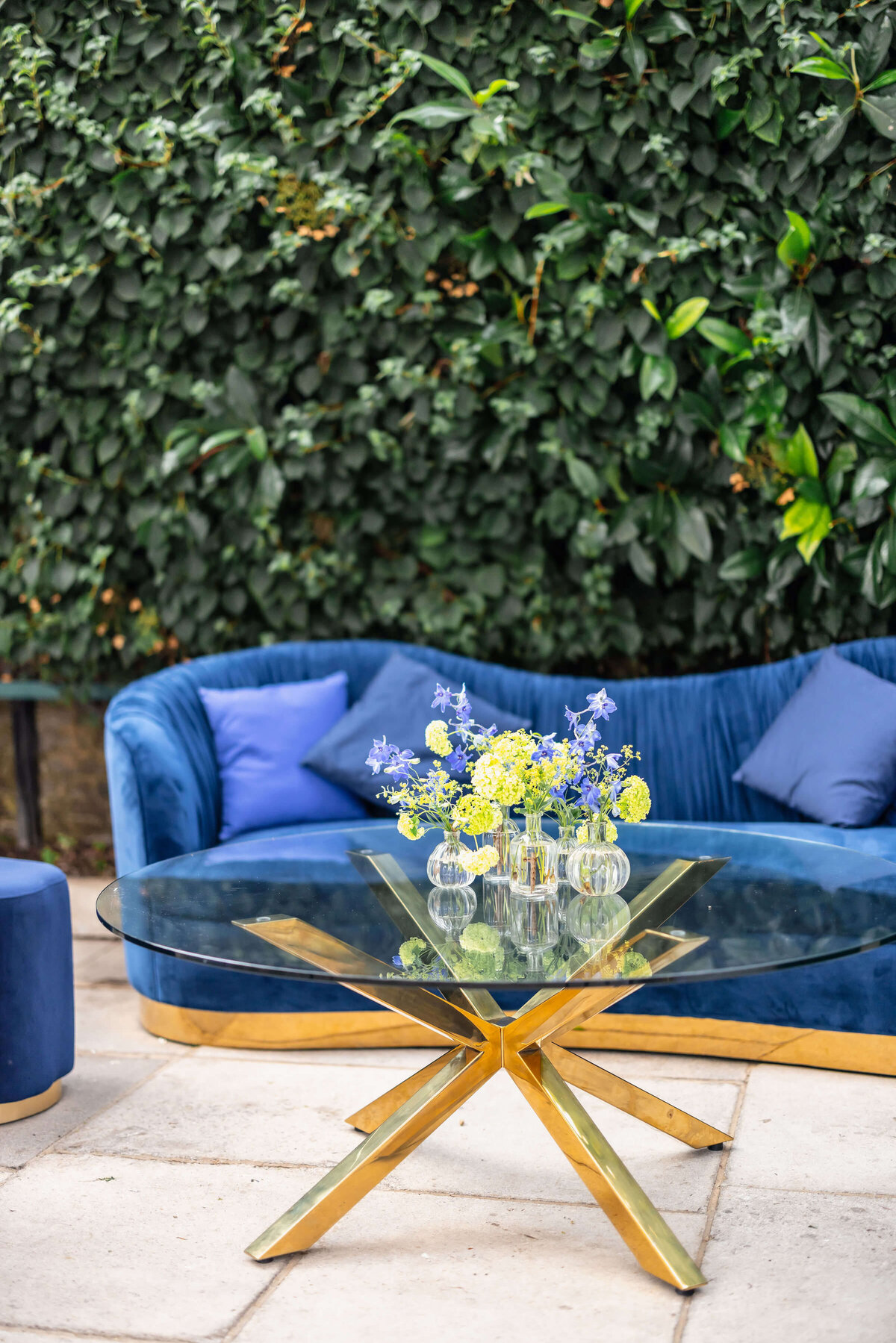 blue lounge seating and coffee table with blue and green flowers on it for a drinks reception at avington park in their orangery