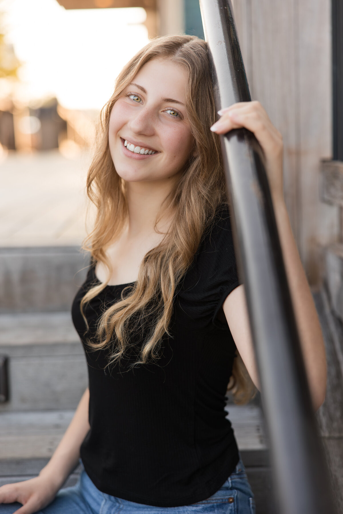 Senior girl seated on stairs smiling at the camera