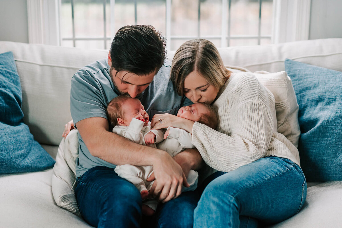 parents kissing twin boys in living room, by Denise Van, a Northern VA newborn photographer