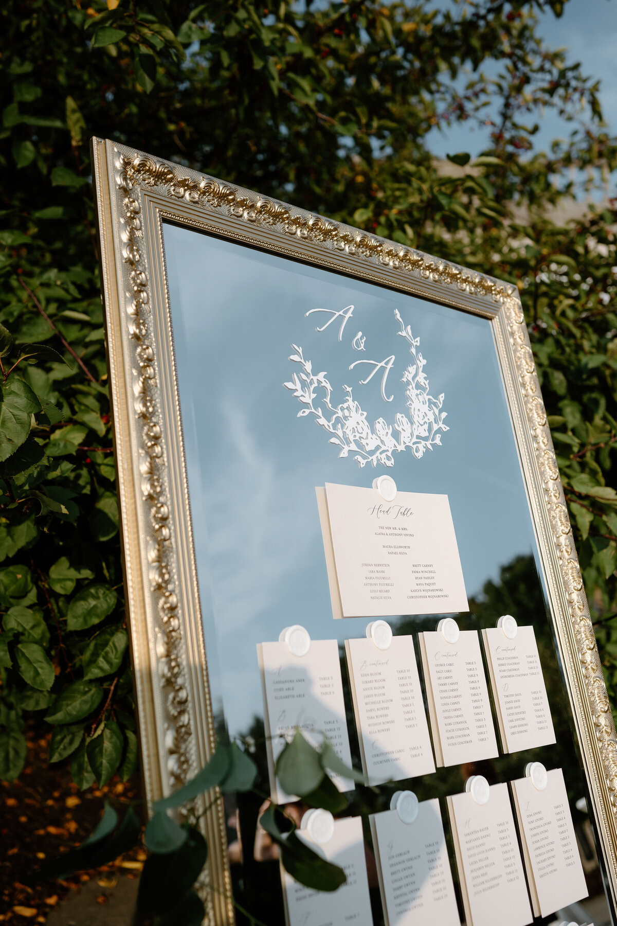 Luxury wedding day stationery display with custom mirror seating chart and floral monogram design.