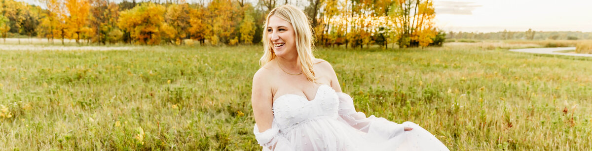 stunning first time mom in a beautiful pearl gown playing with her dress in a field near Green Bay wi