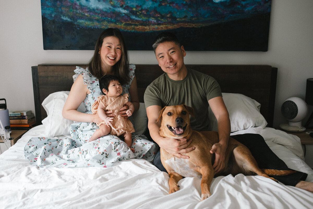 family portrait with a baby and dog in bed